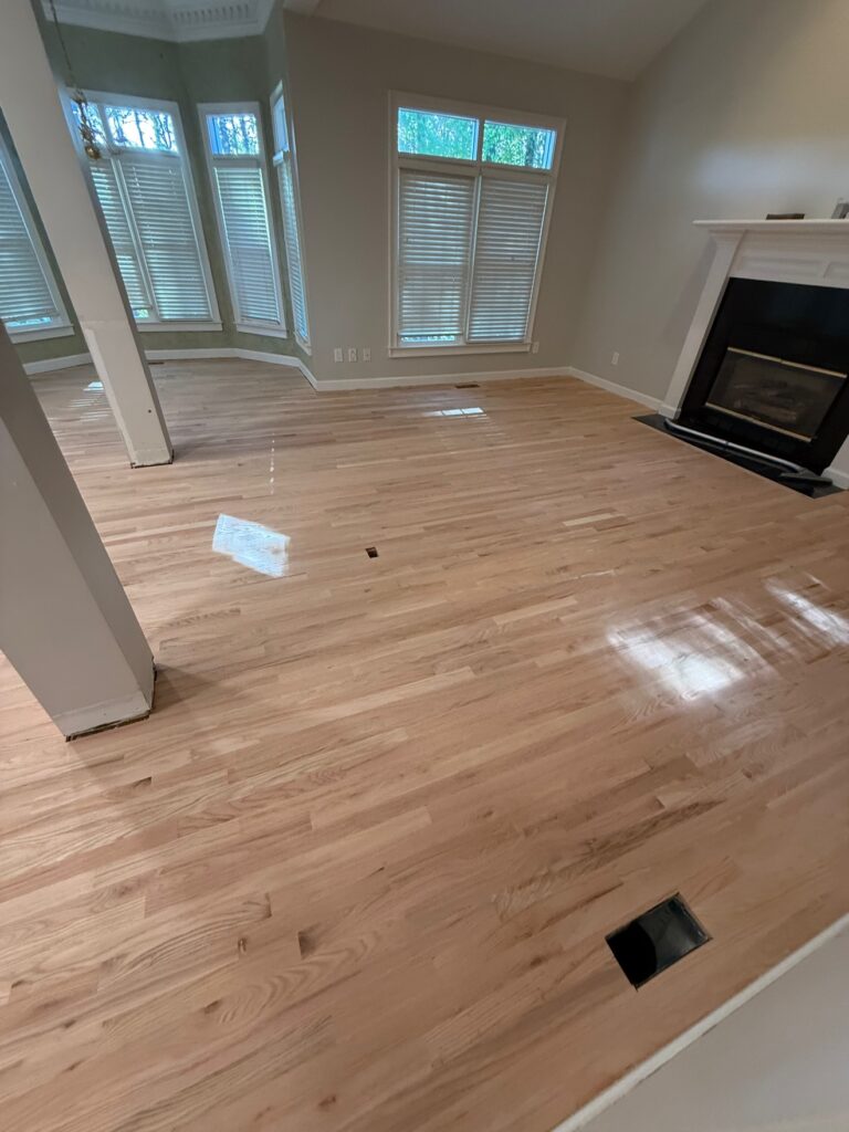 Freshly sanded hardwood floors in a living room with fireplace