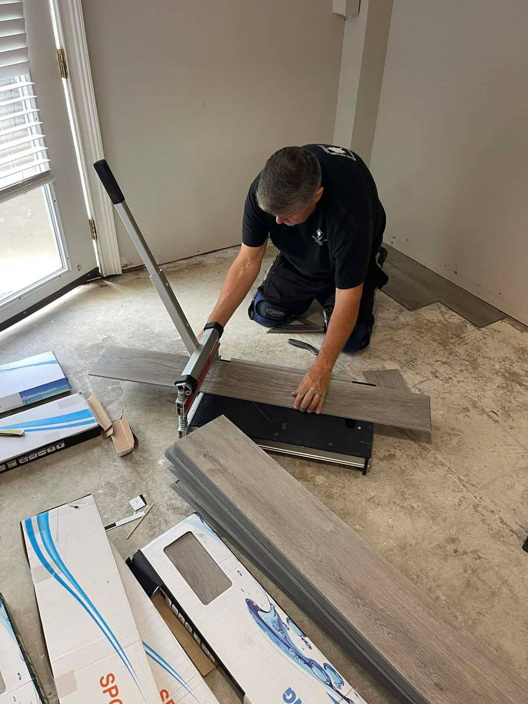 Worker cutting gray planks with a flooring cutter