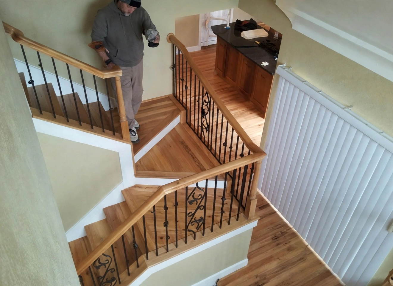 Worker standing on a refinished staircase landing with iron railings