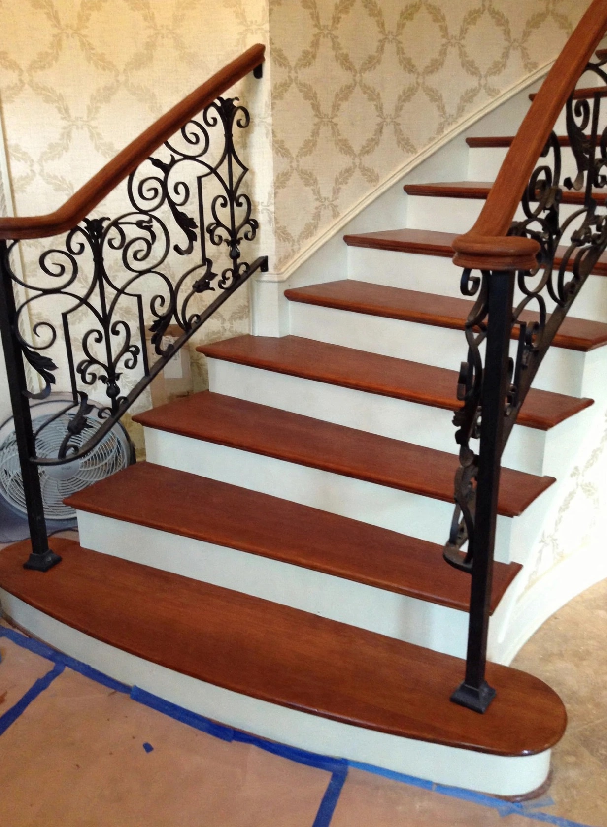 Finished hardwood stair treads with ornate iron railings