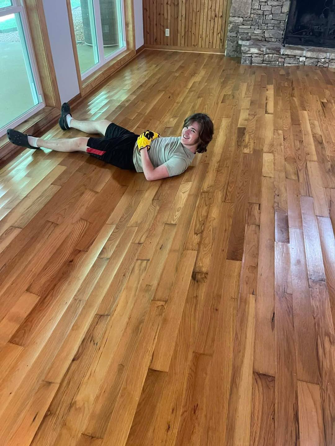 Worker on finished hickory floor in stone fireplace room