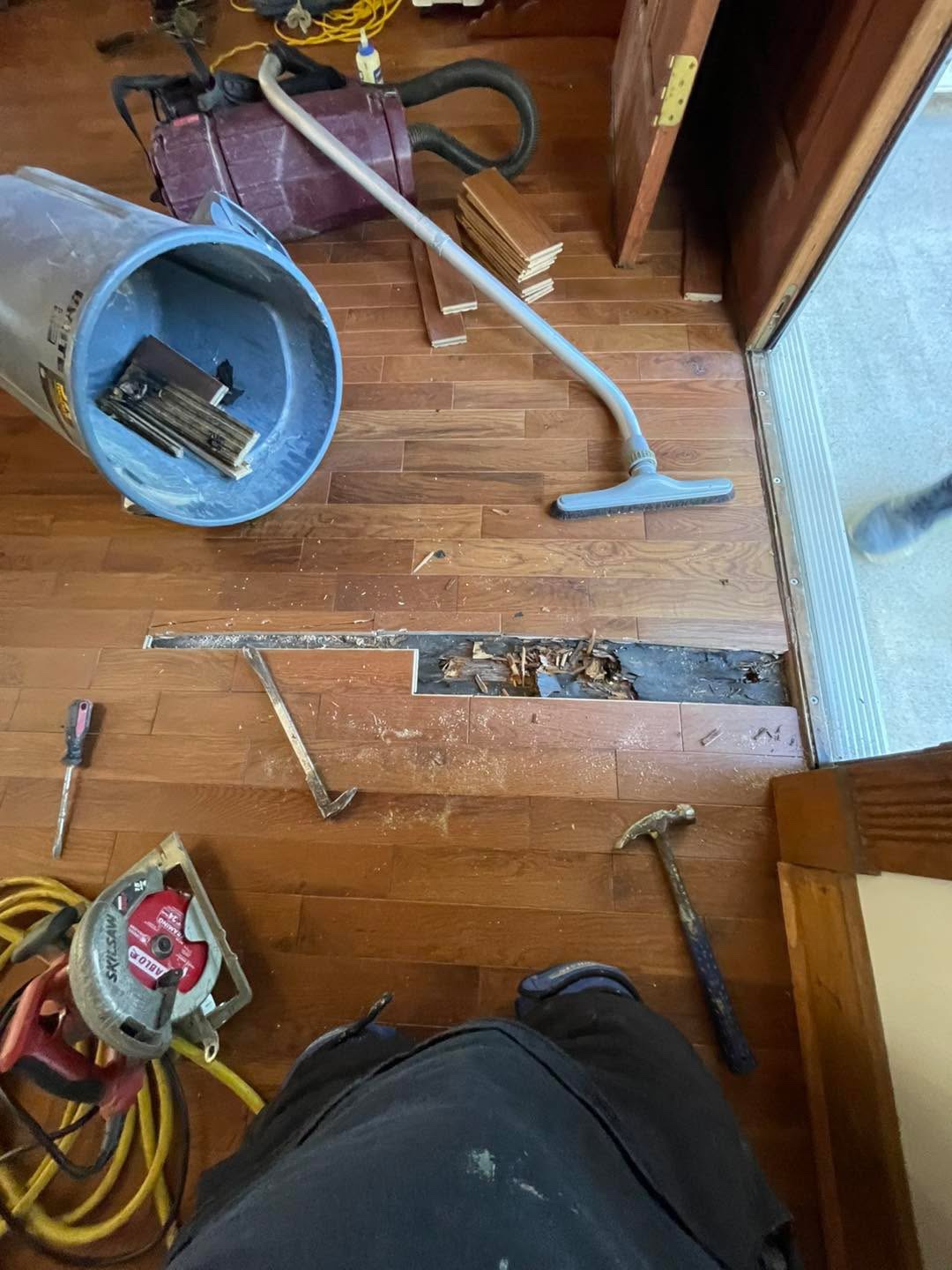 Repair near doorway with vacuum, hammer, and removed board section